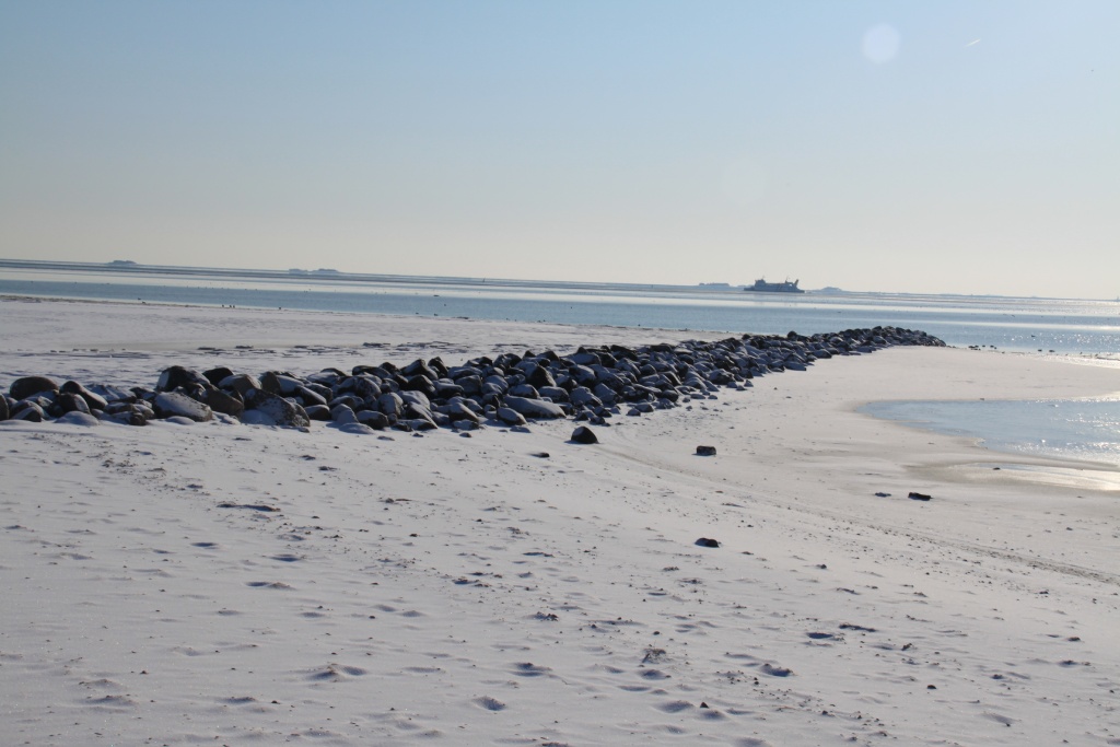 03.02.2012: Nieblum, Strand am Horizont die Fähre von Amrum vor den Warften von Langeneß